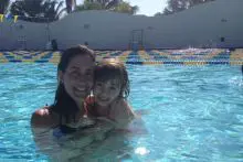 A Lady Swimming trainer with samll kid in the pool